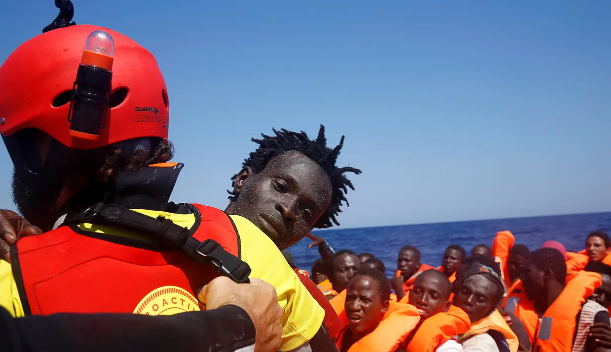 Seorang imigran diselamatkan dari perahu kayu yang disesaki ratusan imigran, di lepas panti Libya, Laut Mediterania, Senin (29/8). Para penjaga pantai Italia berhasil menyelamatkan sekitar 6.500 imigran dari Eritrea dan Somalia. (REUTERS/Giorgos Moutafis)