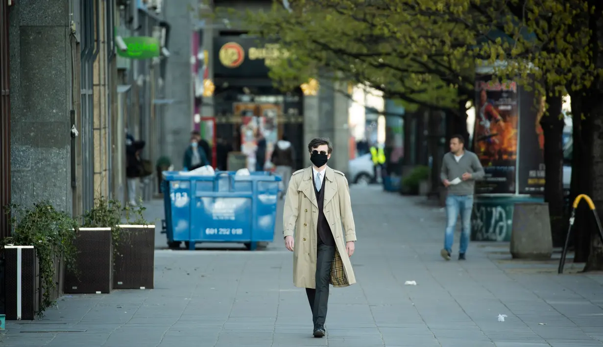 Seorang pria yang mengenakan masker berjalan di sepanjang Jerusalem Avenue yang hampir kosong di Warsawa tengah, Polandia (20/4/2020). Pemerintah Polandia telah melonggarkan beberapa kebijakan pembatasan terkait pandemi COVID-19 pada Senin (20/4). (Xinhua/Jaap Arriens)