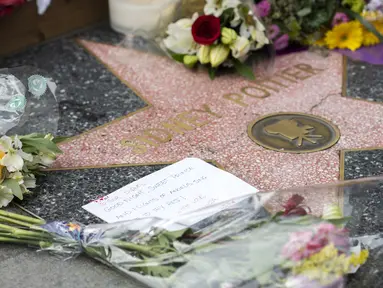 Sebuah catatan dan bunga terlihat pada bintang Sidney Poitier di Hollywood Walk of Fame di Hollywood, California, Jumat (7/1/2022). Poitier, bintang film kulit hitam pertama Hollywood dan pria kulit hitam pertama yang memenangkan aktor terbaik Oscar, meninggal pada usia 94 tahun. (VALERIE MACON/AFP)