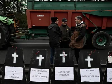 Para petani berdiri di dekat replika peti mati saat berunjuk rasa dan menutup jalan lingkar Bordeaux, Barat Daya Prancis, pada 24 Januari 2024. (Philippe LOPEZ/AFP)