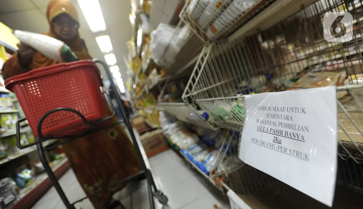 Pembeli berbelanja dekat kertas pemberitahuan pembatasan pembelian gula di supermarket Kawasan Cirendeu, Tangsel, Rabu (18/3/2020). Satgas Pangan meminta pedagang membatasi penjualan bahan pokok yakni beras, gula, minyak goreng dan mi instan, untuk menjaga stabilitas harga. (merdeka.com/Arie Basuki)