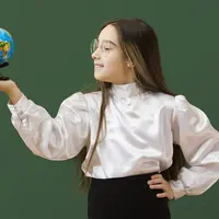 Seorang anak perempuan sedang berkacak pinggang dan memegang sebuah globe (Foto Dok: Freepik/freepik).