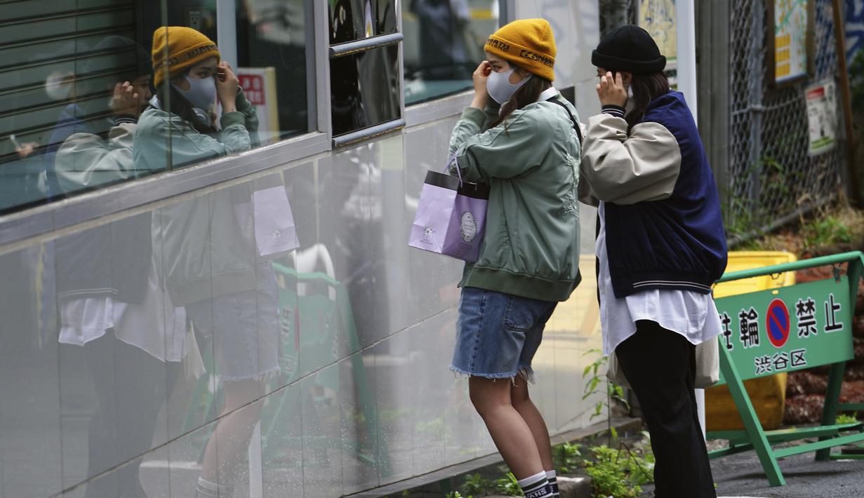 Wanita menyesuaikan pakaian pada awal liburan "Minggu Emas" Jepang di distrik perbelanjaan Shibuya, Tokyo (29/4/2021). "minggu emas" dimulai Kamis (29/4) dalam upaya nasional mengekang kebangkitan cepat kasus virus corona kurang dari tiga bulan sebelum Olimpiade Tokyo. (AP Photo/Eugene Hoshiko)