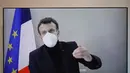 Presiden Prancis Emmanuel Macron terlihat di layar saat dia menghadiri konferensi video, meja bundar untuk Konferensi Kemanusiaan Nasional (NHC), di Kementerian Luar Negeri di Paris, Kamis (17/12/2020). Ini adalah kesekian kalinya pemimpin negara terinfeksi Covid-19. (Charles Platiau/Pool via AP)