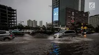 Kendaraan menerobos genangan air di kawasan MH Thamrin, Jakarta, Senin (11/12). Hujan lebat yang mengguyur wilayah Jakarta dan sekitarnya mengakibatkan air setinggi 15 cm menutupi sebagian badan jalan di kawasan tersebut. (Liputan6.com/Faizal Fanani)