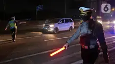Polisi menghalau kendaraan berpenumpang di tol Jakarta-Cikampek untuk keluar ke Gerbang tol Cikarang Barat, Kab. Bekasi, Jumat (24/4/2020). Akses transportasi mobil pribadi dan bus angkutan penumpang dari tol Jakarta Cikampek menuju Karawang ditutup mulai Jumat (24/4). (Liputan6.com/Herman Zakharia)