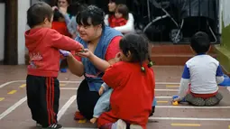 Noelia Garella bermain dengan muridnya di TK Jeromito, Argentina (24/10). Keinginan Noelia menjadi guru TK berawal dari masa kecil yang pahit saat dirinya ditolak masuk ke sebuah sekolah, bahkan dirinya disebut 'Monster'. (AFP Photo/Diego Lima)