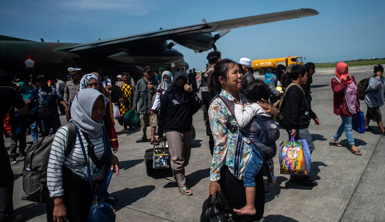 Seorang wanita membawa anaknya ketika mereka tiba di Surabaya, Kamis (4/10). Banyak anak-anak yang terpisah dari keluarganya setelah bencana gempa-tsunami melanda Palu dan Donggala pada 28 September. (AFP Photo/Juni Kriswanto)