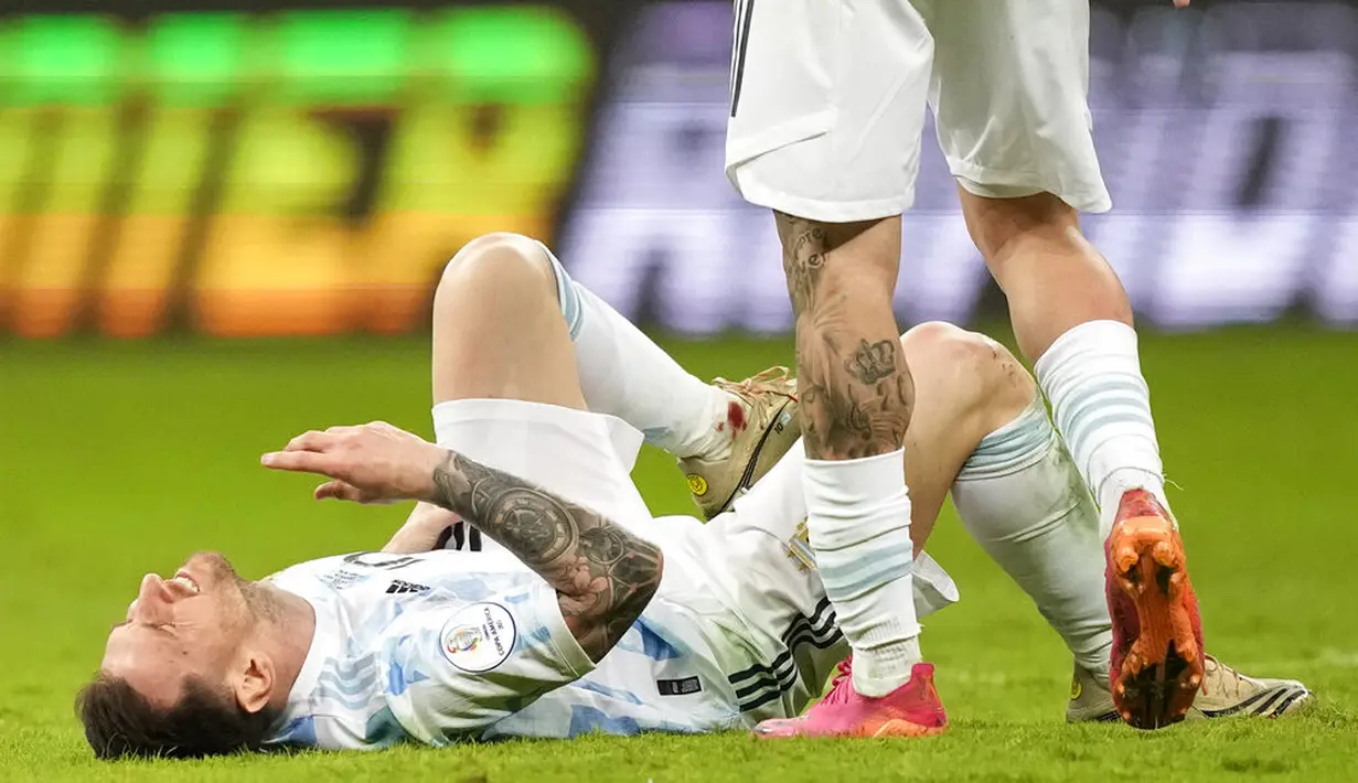 Kapten timnas Argentina, Lionel Messi meringis setelah dilanggar pemain Kolombia pada laga semifinal Copa America 2021 di Estadio Nacional Brasilia, Rabu (7/7/2021).  Argentina lolos ke final usai menang 3-2 atas Kolombia lewat adu penalti. (AP Photo/ Andre Penner)