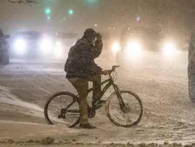 Pesepeda menunggu untuk menyeberangi jalan di tengah badai musim dingin di pusat kota Chicago, AS, 29 Desember 2020. Para komuter pagi di Chicago menghadapi jalanan yang licin dan lalu lintas yang lambat pada Rabu (30/12) saat badai musim dingin besar pertama melanda kota itu. (Xinhua/Joel Lerner)
