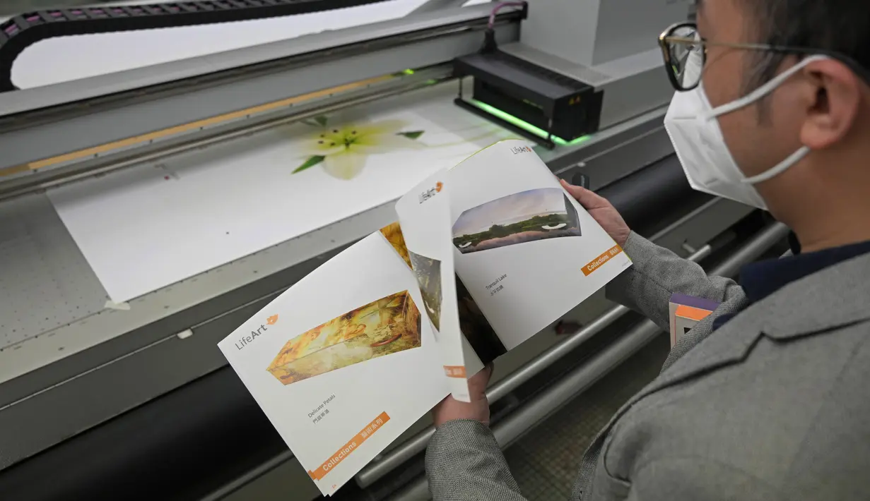 Wilson Tong, CEO LifeArt Asia, melihat katalog pilihan desain peti mati saat mesin sedang mencetak gambar Lily di sampul peti mati, di ong Kong, Jumat, 18 Maret 2022. Perusahaan itu mencoba membuat alternatif peti mati dari kardus yang diklaim ramah lingkungan. (AP Photo/Kin Cheung)