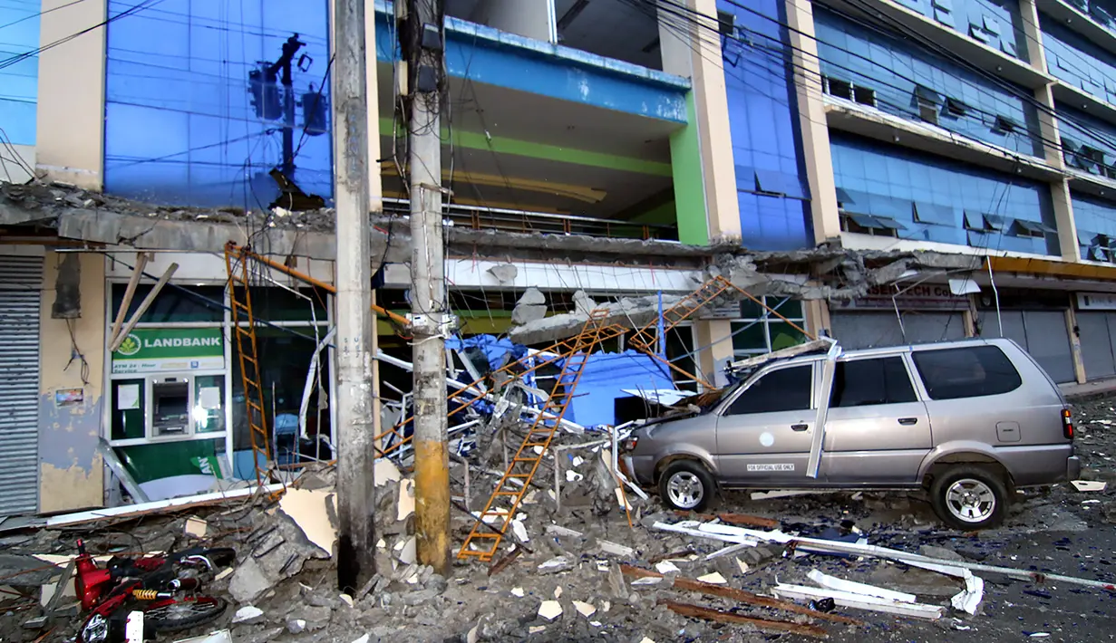 Sebuah mobil tertimpa puing bangunan yang runtuh akibat gempa 6,5 SR yang melanda Surigao City, Pulau Mindanao, Filipina (11/2). Gempa yang terjadi di saat warga sedang lelap tidur itu menghancurkan banyak bangunan, dan bandara. (AFP/Erwin Mascarinas)