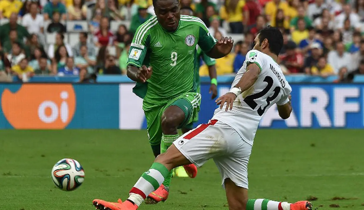Pemain belakang Iran, Mehrdad Pooladi (kanan) mencoba menahan serangan Nigeria yang dibangun lewat kaki Emmanuel Emenike saat berlaga melawan Nigeria di babak penyisihan Piala Dunia Grup F, Baixada Arena, Brasil, (17/6/2014). (AFP PHOTO/Luis Acosta) 