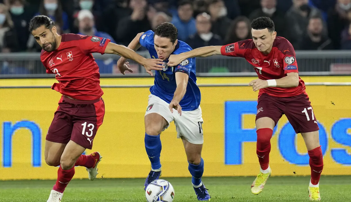 Penyerang Italia, Federico Chiesa berusaha melewati dua pemain Swiss pada pertandingan Grup C kualifikasi Piala Dunia 2022 di stadion Olimpiade Roma, Sabtu (13/11/2021). Italia bermain imbang atas Swiss 1-1.  (AP Photo/Gregorio Borgia)