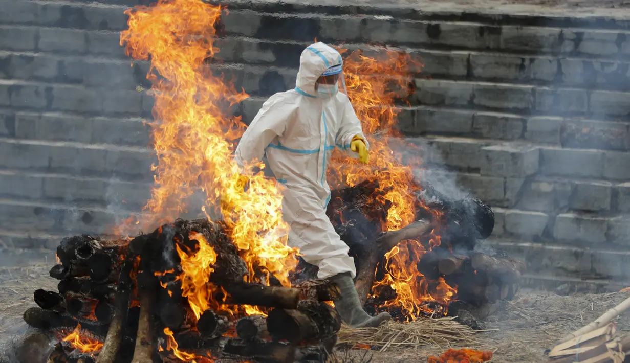 Seorang pria Nepal berjalan di antara dua tumpukan kayu saat mengkremasi jenazah korban COVID-19 di dekat kuil Pashupatinath di Kathmandu, Rabu (5/5/2021). Nepal kewalahan oleh lonjakan Covid-19 ketika wabah India menyebar ke seluruh Asia Selatan. (AP Photo/Niranjan Shrestha)