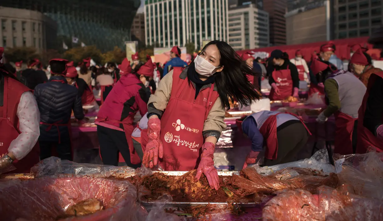 Seorang peserta membuat kimchi, hidangan tradisional Korea Selatan, selama Festival Kimchi tahunan di pusat kota Seoul, Jumat (3/11). Kimchi merupakan makanan yang terbuat dari sawi putih atau lobak yang difermentasikan. (Ed JONES/AFP)