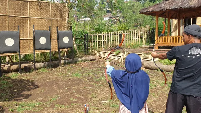 Salah satu instruktur petugas kawasan wisata Kampung Bareto Cisurupan, tengah memberikan intruksi kepada pengunjung cilik saat mencoba permainan tradisional panahan. (Liputan6.com/Jayadi Supriadin)