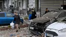 Penduduk setempat membawa barang-barang saat mereka meninggalkan bangunan tempat tinggal bertingkat, yang sebagian hancur setelah serangan pesawat tak berawak pada malam hari di Kyiv pada 30 Mei 2023. (Sergei SUPINSKY/AFP)