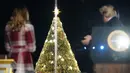 Presiden AS Donald Trump dan Ibu Negara Melania Trump bertepuk tangan saat upacara penerangan pohon cemara, yang menjadi Pohon Natal Nasional di taman sebelah selatan Gedung Putih, Kamis (5/12/2019). Pohon cemara setinggi 30 kaki tersebut dihiasi 50.000 lampu dan 450 bintang. (MANDEL NGAN / AFP)