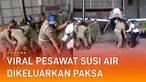 Sejumlah Satpol PP bergotong royong menarik pesawat dan perlengkapannya.