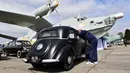 Seorang pengunjung melihat ke mobil di sebelah pesawat selama hari pembukaan festival mobil retro OldCarLand di Kiev (27/4). Pameran kendaraan jadul ini digelar dari 27 April hingga Mei, 1, 2018. (AFP Photo/Sergei Supinsky)