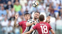 Aksi pemain Juventus, Miralem Pjanic menyundul bola melewati dua pemain Cagliari pada laga Serie A di  Turin, (19/8/2017). Juventus menang 3-0. (Alessandro Di Marco/ANSA via AP)