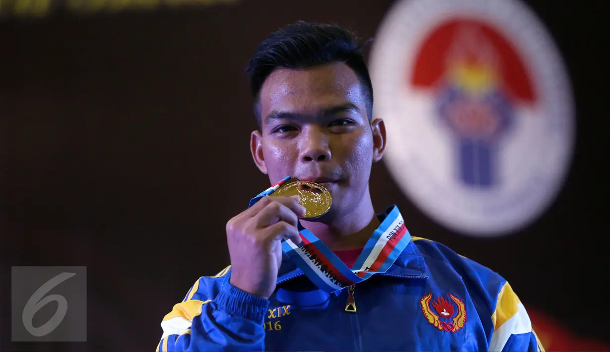 Lifter Lampung, Viky Aryanto memamerkan medali emas kelas 66 kg putra PON XIX di GOR Sabilulungan, Kab Bandung, Minggu (25/9). Viky merebut emas di kelas 66 kg dengan total angkatan 798 kg. (Liputan6.com/Helmi Fithriansyah)