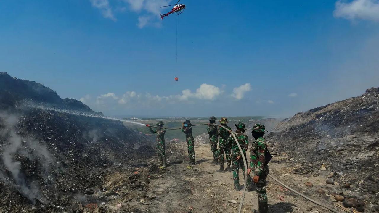 Anggota Raider 900/SBW TNI AD dan Helikopter Badan Nasional Penanggulangan Bencana (BNPB) saat berupaya memadamkan sisa api kebakaran sampah di Tempat Pembuangan Akhir (TPA) Regional Sarbagita Suwung, Denpasar, Bali, Jumat (20/10/2023).