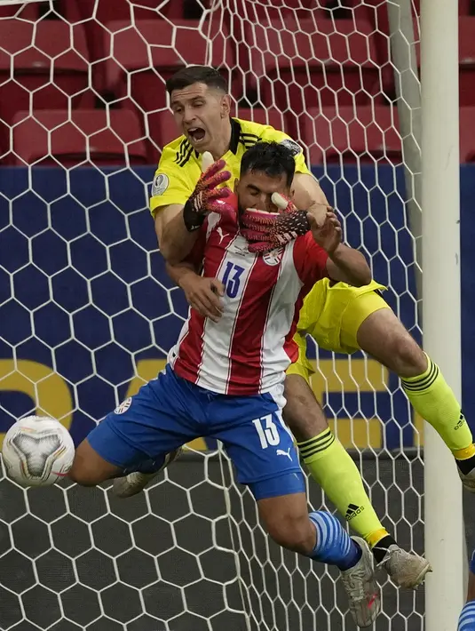 Kiper Argentina, Emiliano Martinez berusaha menyelamatkan bola dari pemain Paraguay, Alberto Espinola pada pertandingan grup A Copa America 2021 di Stadion Nasional, Brasil, Selasa (22/6/2021). Berkat hasil ini, Argentina sementara duduk di puncak klasemen dengan poin 7. (AP Photo/Ricardo Mazalan)