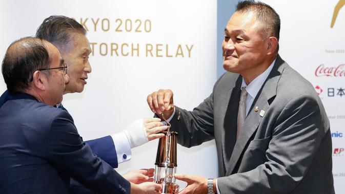 Presiden Komite Olimpiade Jepang, Yasuhiro Yamashita (kanan) menerima Api Olimpiade dari Presiden Panitia Penyelenggara Tokyo 2020, Yoshiro Mori saat upacara untuk dipamerkan ke publik di Museum Olimpiade Jepang di Tokyo pada Senin (31/8/2020). (Rodrigo Reyes Marin/Pool Photo via AP)