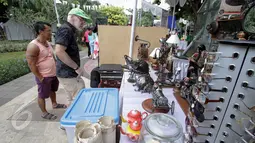 Seorang turis asing tampak melihat salah satu kios barang antik di Pasar Maci atau pasar barang-antik di Taman Menteng, Jakarta, Minggu (31/5). Acara tersebut menjual sejumlah barang antik. (Liputan6.com/Faizal Fanani)