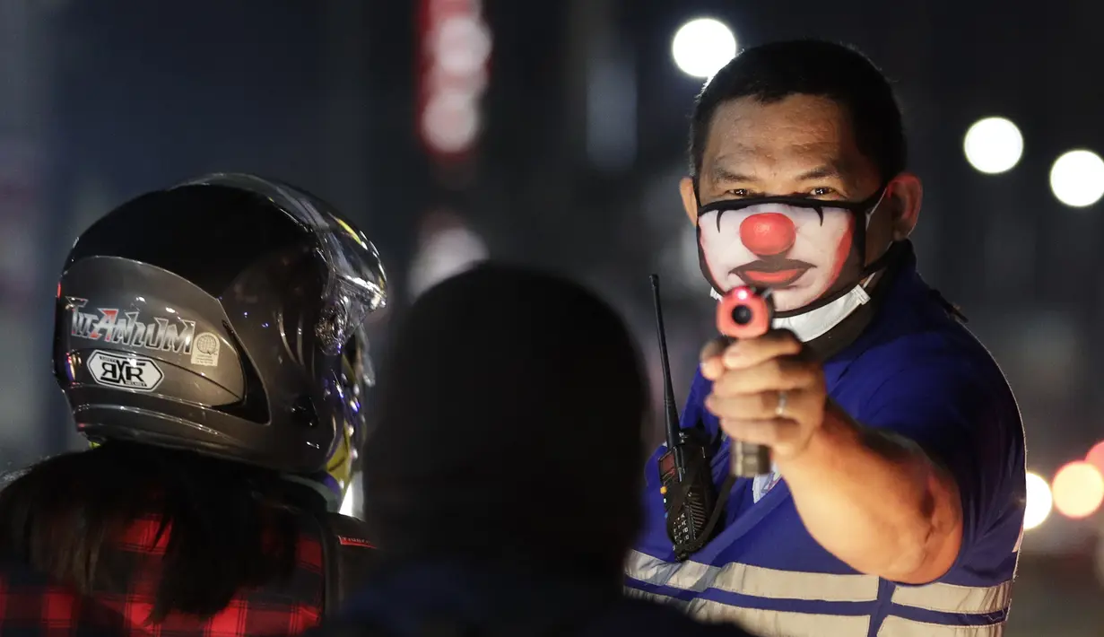 Petugas desa memeriksa suhu tubuh warga di pos pemeriksaan virus corona COVID-19 di Manila, Filipina, Senin (16/3/2020). Polisi beserta petugas lalu lintas dan petugas desa melakukan pengecekan suhu tubuh warga untuk mencegah penyebaran virus corona COVID-19. (AP Photo/Aaron Favila)