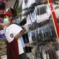 Pembeli mencoba seragam sekolah baru kepada anaknya di salah satu toko di Tangerang, Banten, Selasa (2/6/2020). Menjelang tahun ajaran baru, sejumlah pedagang di tempat tersebut mengeluh karena omzet penjualan seragam sekolah menurun drastis akibat pandemi COVID-19. (Liputan6.com/Angga Yuniar)
