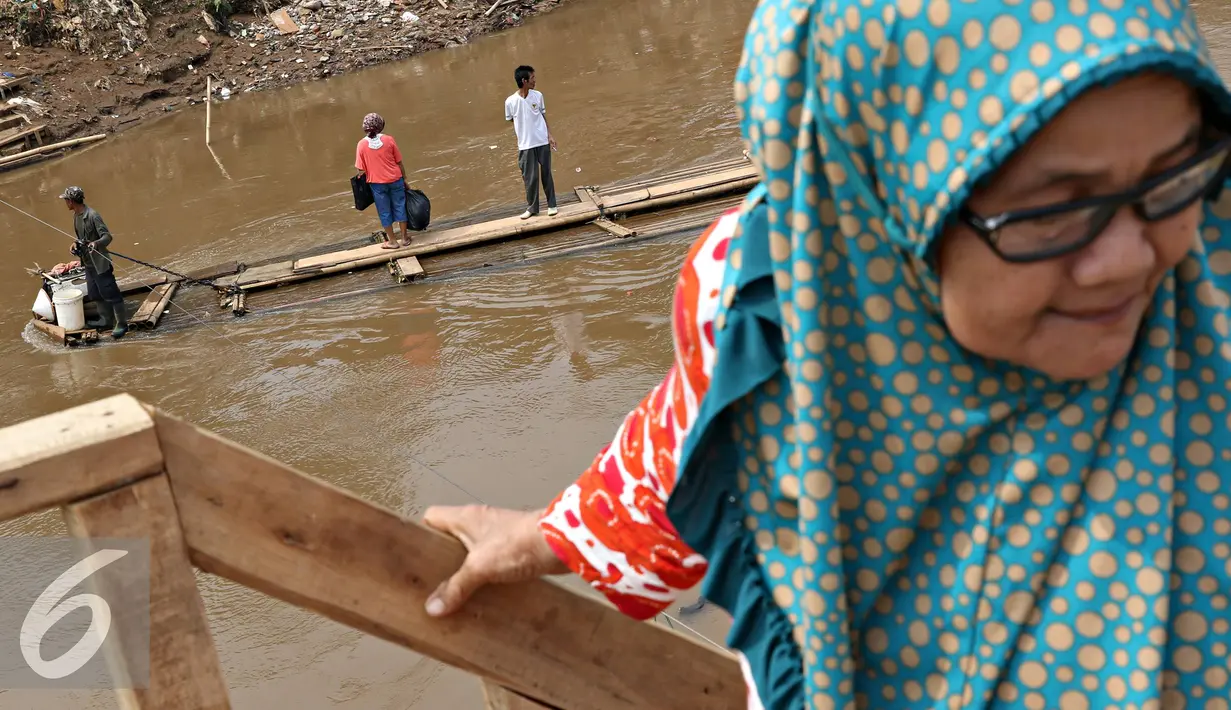 Warga menaiki eretan untuk menyeberangi Kali Ciliwung, Jakarta, Senin (30/11). Tidak adanya fasilitas jembatan menyebabkan warga memilih eretan sebagai sarana penyeberangan sehari-hari, meskipun dengan kondisi seadanya. (Liputan6.com/Immnuel Antonius)