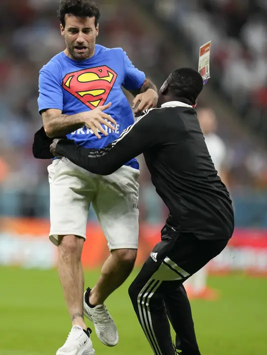 Petugas saat menangkap seorang pria yang masuk ke lapangan dengan membaw abendera pelangi selama pertandingan grup H Piala Dunia 2022 antara Portugal dan Uruguay, di Stadion Lusail di Lusail, Qatar, Senin, 28 November 2022. (AP Photo/Petr David Josek)