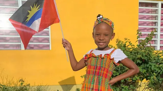 Seorang anak asal Antigua dan Barbuda memegang bendera negaranya