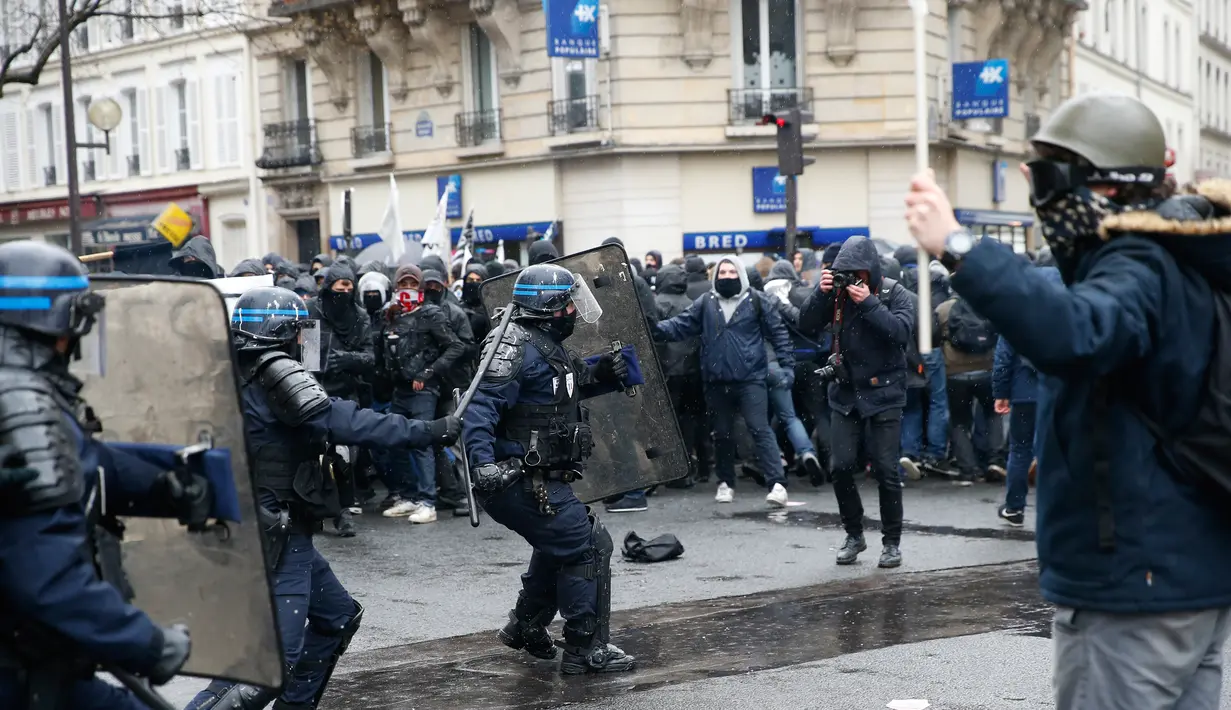 Pengunjuk rasa berhadapan dengan polisi anti huru hara saat unjuk rasa di ibukota Prancis, Paris, Kamis (31/3). Mereka menolak rancangan undang-undang sosialis pemerintah Prancis yang dinilai merugikan pekerja. (Thomas SAMSON/AFP)