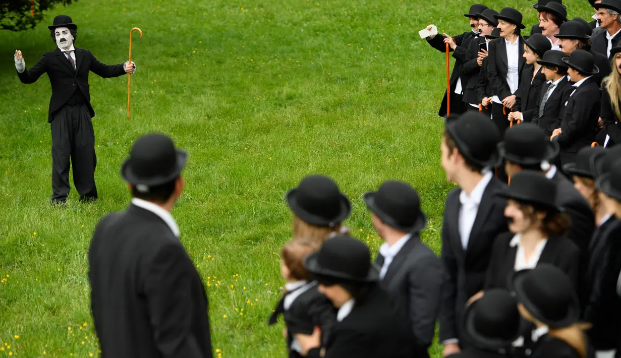 Seorang penggemar menirukan tingkah konyol Charlie Chaplin saat menggelar pertemuan di Corsier sur Vevey, Swiss, Minggu (16/4). Pertemuan yang dihadiri 662 orang itu dalam rangka merayakan HUT ke-128 Charlie Chaplin. (Laurent Gillieron/Keystone via AP)