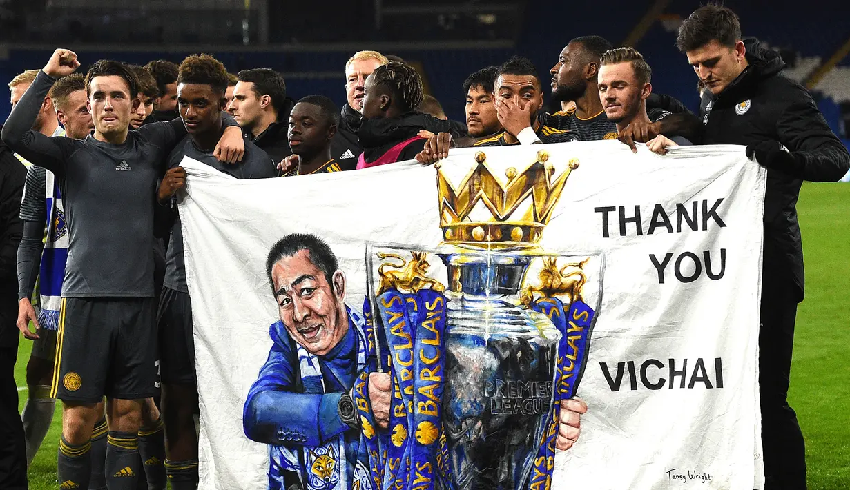 Para pemain Leicester membentangkan spanduk bergambar Vichai Srivaddhanaprabha usai mengalahkan Cardiff di Stadion Cardiff City, Wales, Sabtu (3/11). Hal ini dilakukan untuk mengenang wafatnya pemilik The Foxes. (AFP/Oli Scarff)