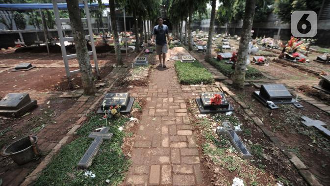 Peziarah melintasi makam yang mengisi sebagian jalan di kompleks pemakaman Paroki Gereja St Servatius, Kampung Sawah, Bekasi, Jawa Barat, Kamis (26/12/2019). (merdeka.com/Iqbal Nugroho)