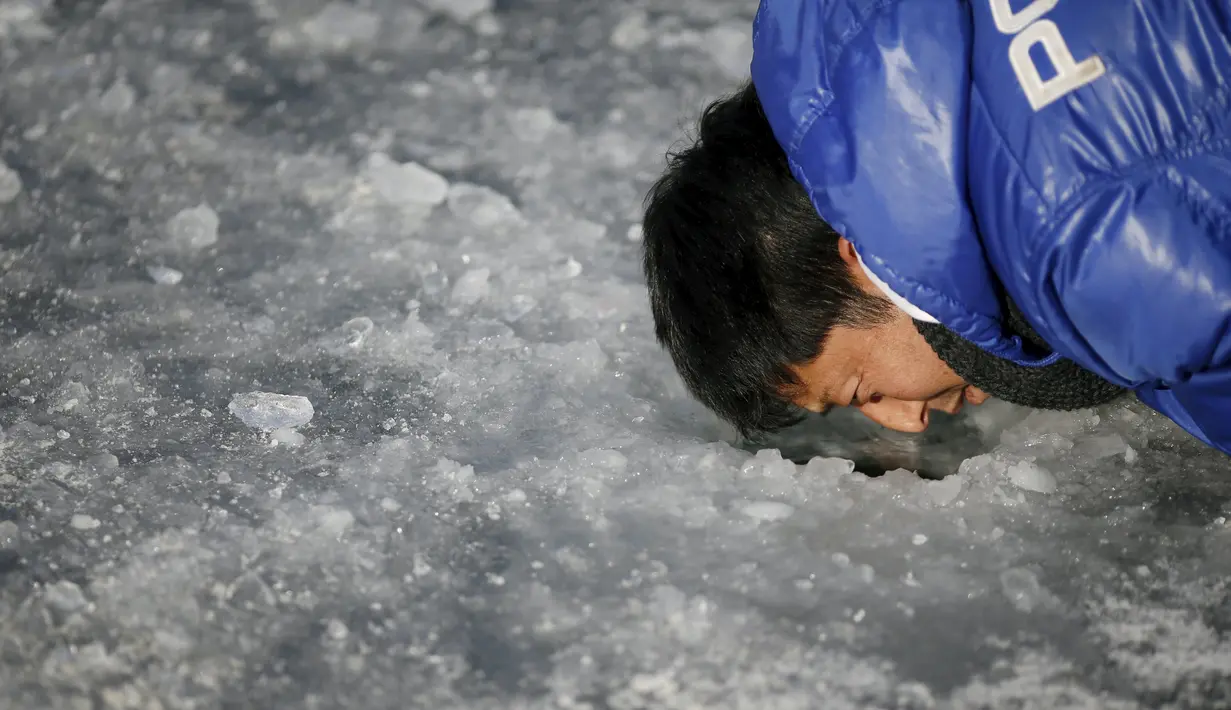 Seorang warga mencari ikan air tawar di lubang kecil selama acara Festival Es di sungai yang beku di Hwacheon, selatan dari zona demiliterisasi (DMZ) yang memisahkan dua Korea, (9/1/2016). (REUTERS/Kim Hong-Ji)