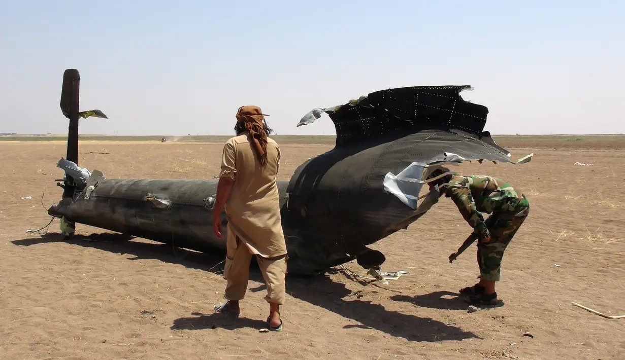Pemberontak Suriah memeriksa salah satu bagian pesawat milik Rusia yang ditembak jatuh di wilayah Idlib, Suriah, Senin (1/8). Belum ada kelompok yang mengaku bertanggung jawab atas jatuhnya helikopter Mi-8 tersebut. (Mohamed al - Bakour/AFP)