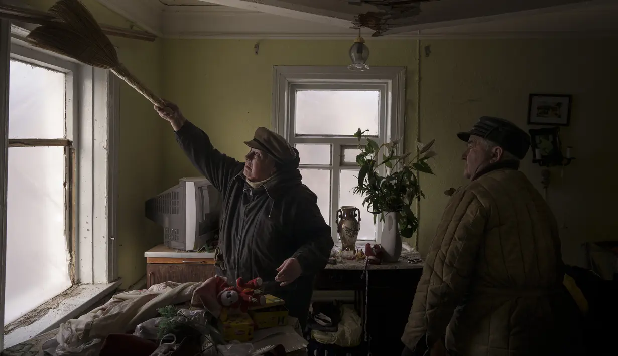 Galina membantu membersihkan rumah tetangga yang rusak akibat bom Rusia di Baryshivka, timur Kiev, Ukraina, pada Jumat (11/3/2022). Invasi Rusia ke Ukraina sudah memasuki hari ke-16 pada hari Jumat ini. (AP Photo/Felipe Dana)