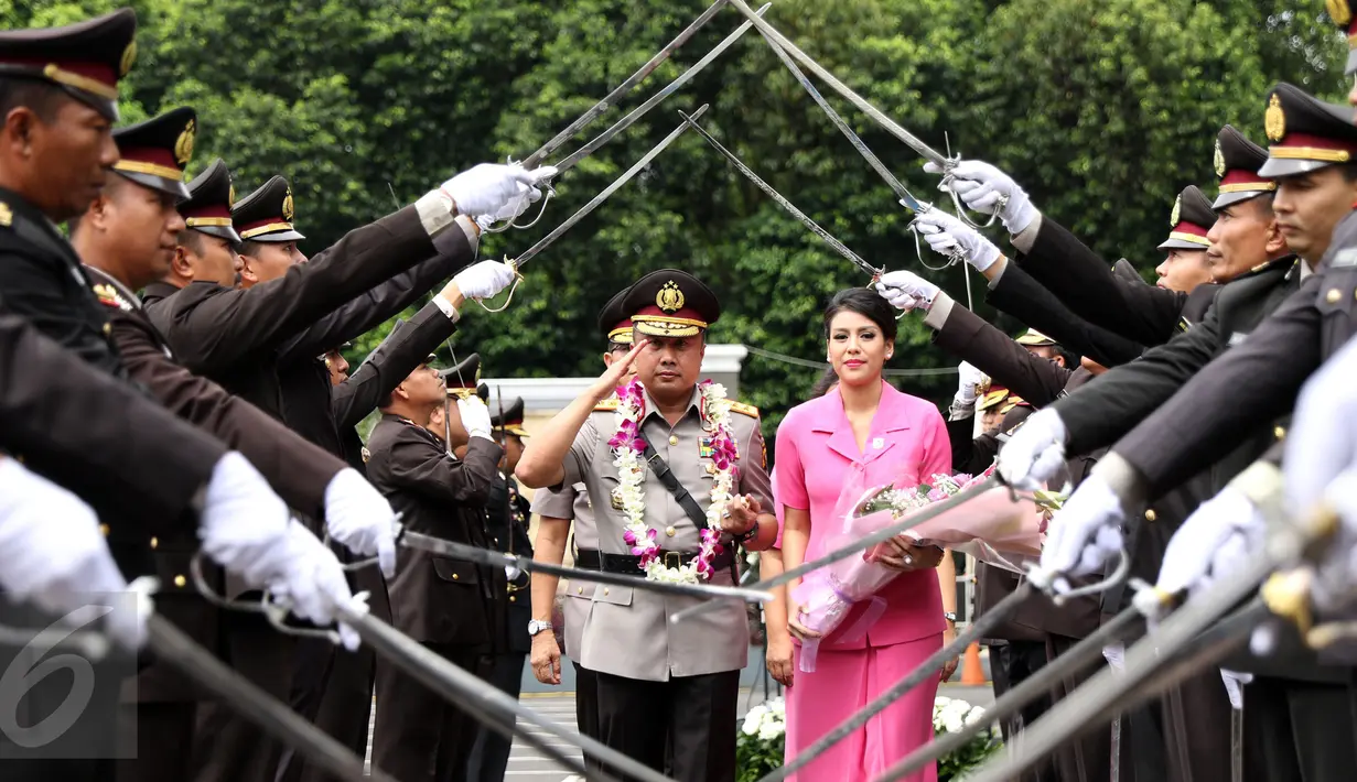 Irjen Pol Agung Budi M bersama istri melewati tradisi pedang pora usai upacara pelepasan jabatan Kakorlantas Polri di Jakarta, Rabu (4/1). Selanjutnya, Irjen Pol Agung Budi M menjabat Kapolda Sumsel. (Liputan6.com/Helmi Fithriansyah)