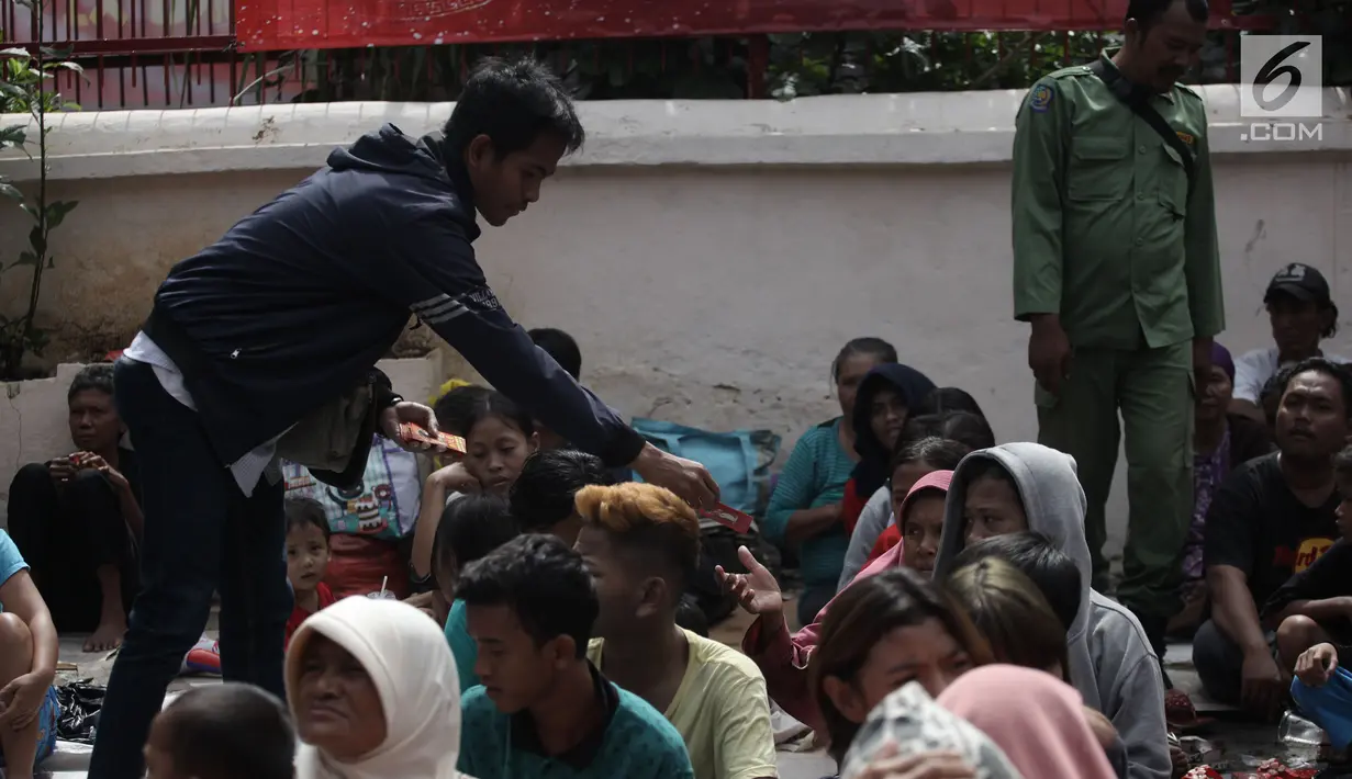 Warga membagikan angpao kepada pengemis di depan Vihara Dharma Bhakti, Petak Sembilan Glodok, Jakarta Barat, Jumat (16/2). Pengemis musiman datang dari pelosok Jakarta memadati Vihara Dharma Bhakti pada perayaan Imlek 2018. (Liputan6.com/Arya Manggala)