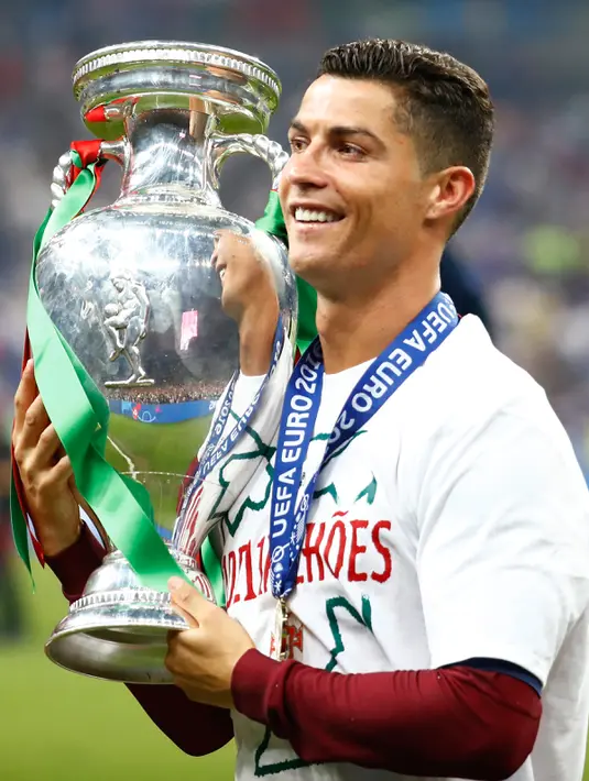 Cristiano Ronaldo berpose dengan tropi Piala Eropa 2016 usai mengalahkan Prancis 1-0 di Stade de France, Senin (11/7). Ronaldo menjadi Pencetak Gol Terbanyak sepanjang perhelatan Piala Eropa berlangsung sebanyak 9 gol. (REUTERS)