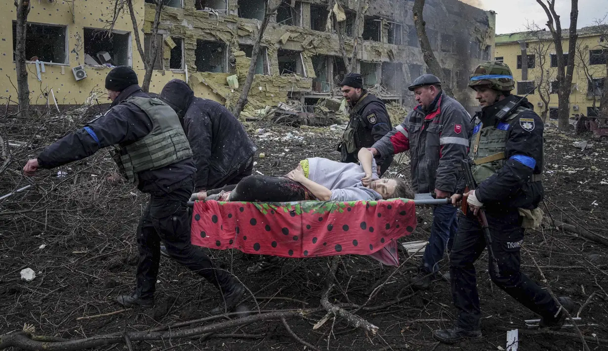 Petugas dan relawan darurat Ukraina membawa seorang wanita hamil yang terluka dari rumah sakit bersalin yang rusak akibat penembakan di Mariupol, Ukraina, Rabu, 9 Maret 2022. Bayi itu lahir dalam keadaan meninggal. Setengah jam kemudian, sang ibu meninggal juga. ((AP Photo/Evgeniy Maloletka)