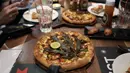 <p>Pizza dengan daun ganja disajikan kepada pelanggan di sebuah restoran di Bangkok, Thailand pada 24 November 2021. Thailand pada Februari tahun ini mengizinkan bagian tertentu dan ekstrak ganja untuk digunakan dalam makanan dan minuman. (AP Photo/Sakchai Lalit)</p>
