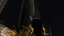 Warga mengabadikan titik api yang masih tersisa di Gedung Neo Soho, Jakarta Barat, Rabu (9/11). Gedung Neo Soho sempat terbakar hebat hampir di setiap lantainya. (Liputan6.com/Faizal Fanani)