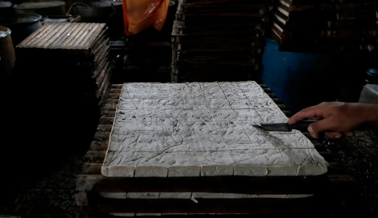 Pekerja memotong tahu yang baru dicetak, di sebuah industri tahu rumahan di pinggiran Jakarta, Rabu (10/7/2019). Karena populernya, tahu menjadi bagian tak terpisahkan yang ditemui di tempat makan berbagai tingkat sosial di Indonesia, bersama-sama dengan tempe. (AP Photo/Tatan Syuflana)